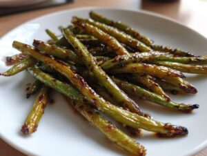 A close-up of perfectly cooked chinese green beans with garlic sauce glistening on a white plate.