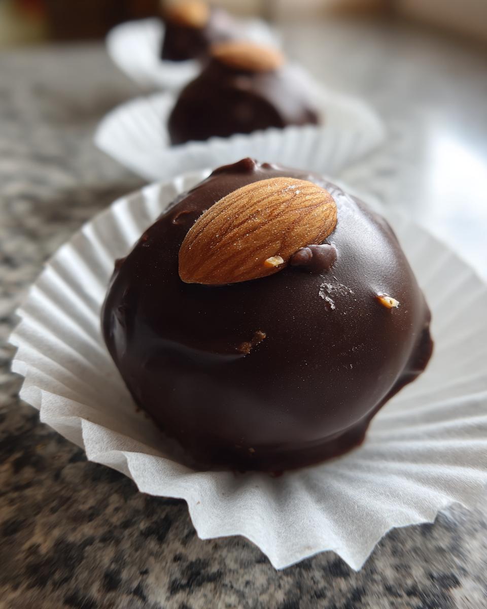 Close-up of a rich, dark chocolate coated almond joy truffles topped with a whole almond.