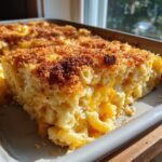 A thick slice of creamy baked mac and cheese recipe with a golden, crispy breadcrumb topping.