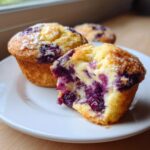 Close-up of a blueberry cream cheese muffin broken open showing the gooey cream cheese center and berries.