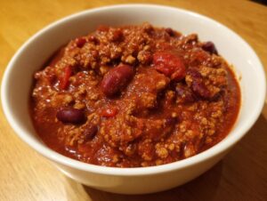 Close-up of a hearty bowl of rich, red high protein chili featuring ground meat and visible kidney beans.