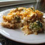 A serving of creamy chicken broccoli rice casserole topped with melted cheddar cheese and parsley.