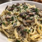 A close-up view of rich, creamy mushroom pasta tossed with fettuccine and topped with sautéed mushrooms and fresh parsley.