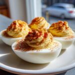 Four perfectly prepared deviled eggs, piped high with filling and sprinkled with paprika.