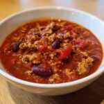 Close-up of a hearty bowl of high protein chili featuring ground meat, kidney beans, and tomatoes in a rich sauce.