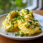 Three scoops of creamy, yellow garlic butter mixture topped generously with chopped fresh parsley and black pepper.
