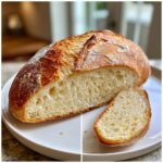 A loaf of freshly baked Italian bread, sliced open to show the airy, open crumb structure and golden crust.