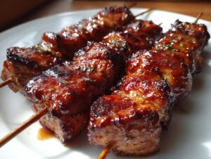 Close-up of juicy honey garlic chicken skewers with a rich, glossy glaze resting on a white plate.