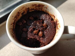 Close-up overhead shot of a moist chocolate mug cake topped with chocolate chips inside a white mug.