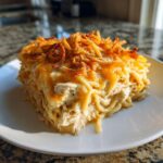 A square serving of creamy monterey chicken spaghetti topped with melted cheese and crispy fried onions.