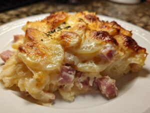 Close-up of a rich serving of scalloped potatoes and ham, featuring creamy sauce and a golden, bubbly cheese crust.