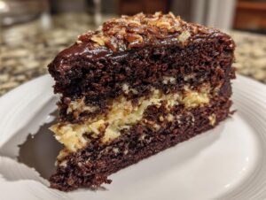 A close-up of a moist slice of german chocolate cake recipe showing dark chocolate layers and coconut-pecan filling.