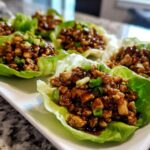 Close-up of several delicious chicken lettuce wraps filled with savory ground chicken mixture and topped with green onions.