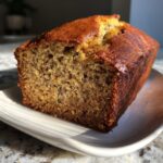 A close-up of a freshly baked slice of the best banana bread, showing its moist crumb and golden-brown crust.