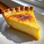 A close-up slice of creamy buttermilk pie with a golden, slightly caramelized top crust.