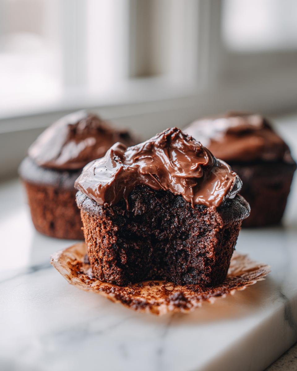A chocolate cinnamon roll with a bite taken out, showing its moist interior and rich chocolate frosting. Focus on chocolate cinnamon rolls.