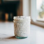 A glass mason jar filled with creamy coconut chia pudding, ready to eat.