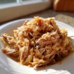 Close-up of shredded pork and sauerkraut mixture served on a white plate, highlighting the tender meat.