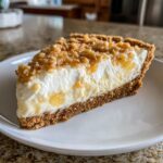 A decadent slice of million dollar pie featuring a graham cracker crust, creamy filling, and nut topping.