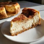 A perfect slice of creamy snickerdoodle cheesecake dusted heavily with cinnamon sugar.