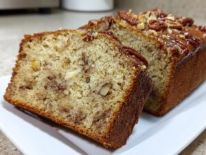 Close-up of two slices of moist Sweet Alabama Pecan Bread topped with glazed pecans.